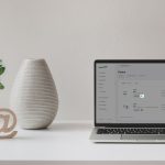 Styled desk with a laptop, vase and decorations. The laptop screen shows an email marketing automation workflow. And Marketing logo in white in bottom left corner.